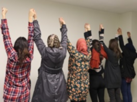 Imatge d'un grup de dones d'esquenes agafades de les mans amb els braços enlairats